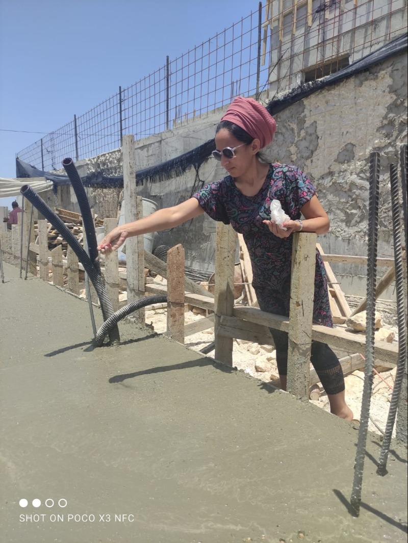 ציפיה מפזרת חול מנצרים ביסודות הבית החדש