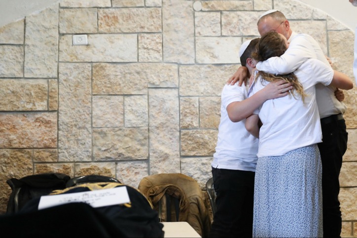 אב המשפחה מחבק את ילדיו הנותרים בהלוויה